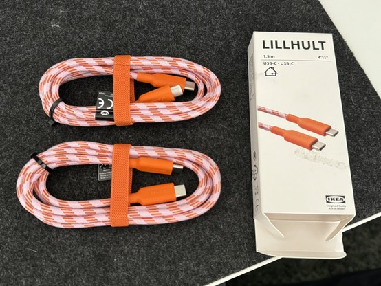 Two orange and white braided USB-C cables next to their IKEA LILLHULT packaging.