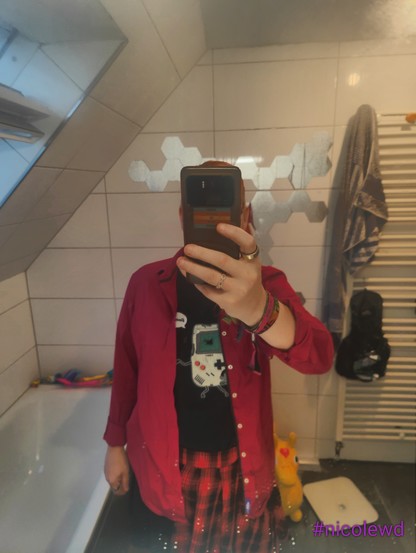 Mirror selfie of me wearing a black T-shirt, a red/black plaid skirt and a wine red shirt.
It looks not even bad, given I always hates wearing formal shirts before transitioning.