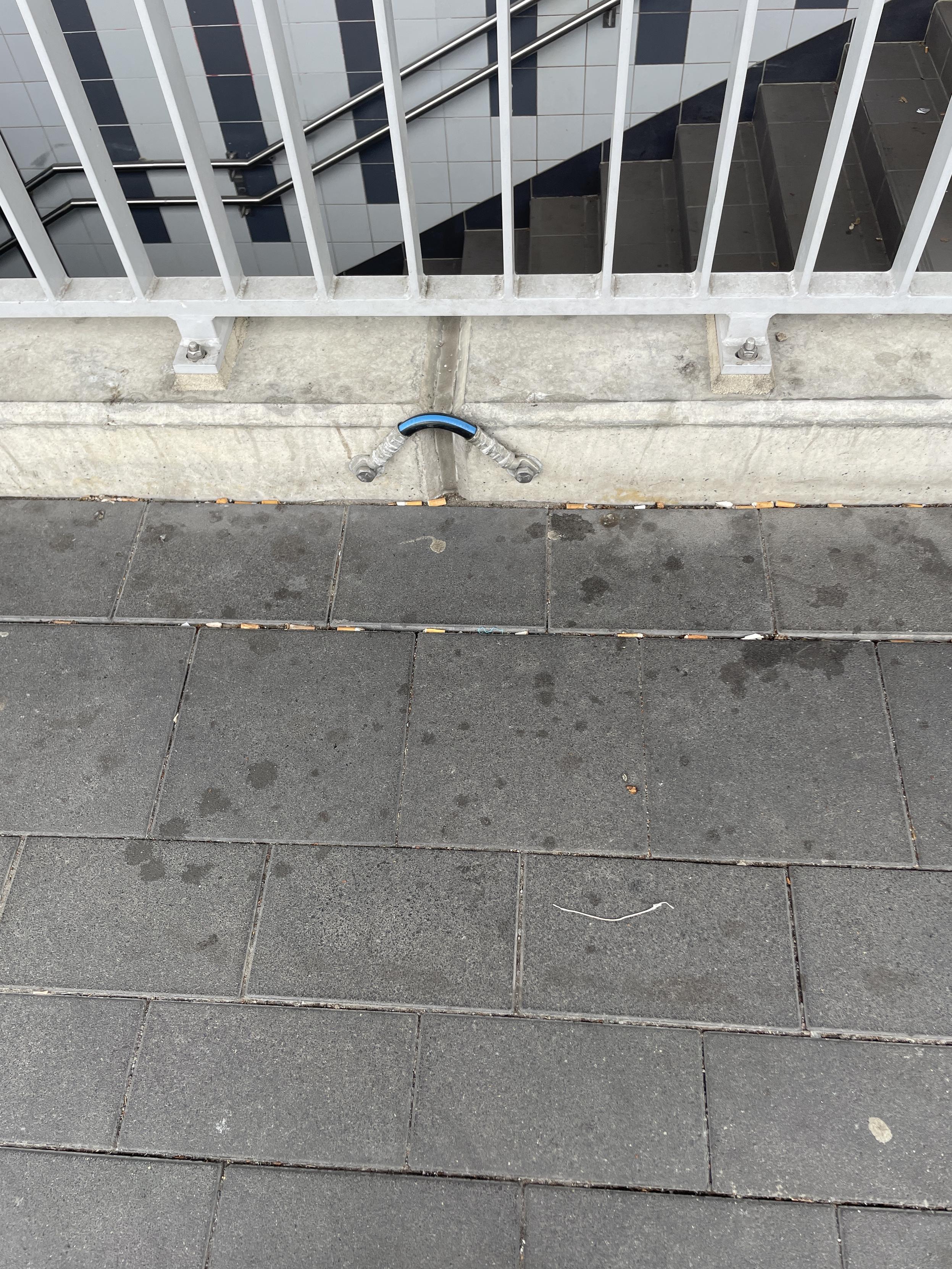 Ein dickes Kabel zwischen zwei Betonbauelemeneten. Oben sieht man das Geländer und unten die Treppe.